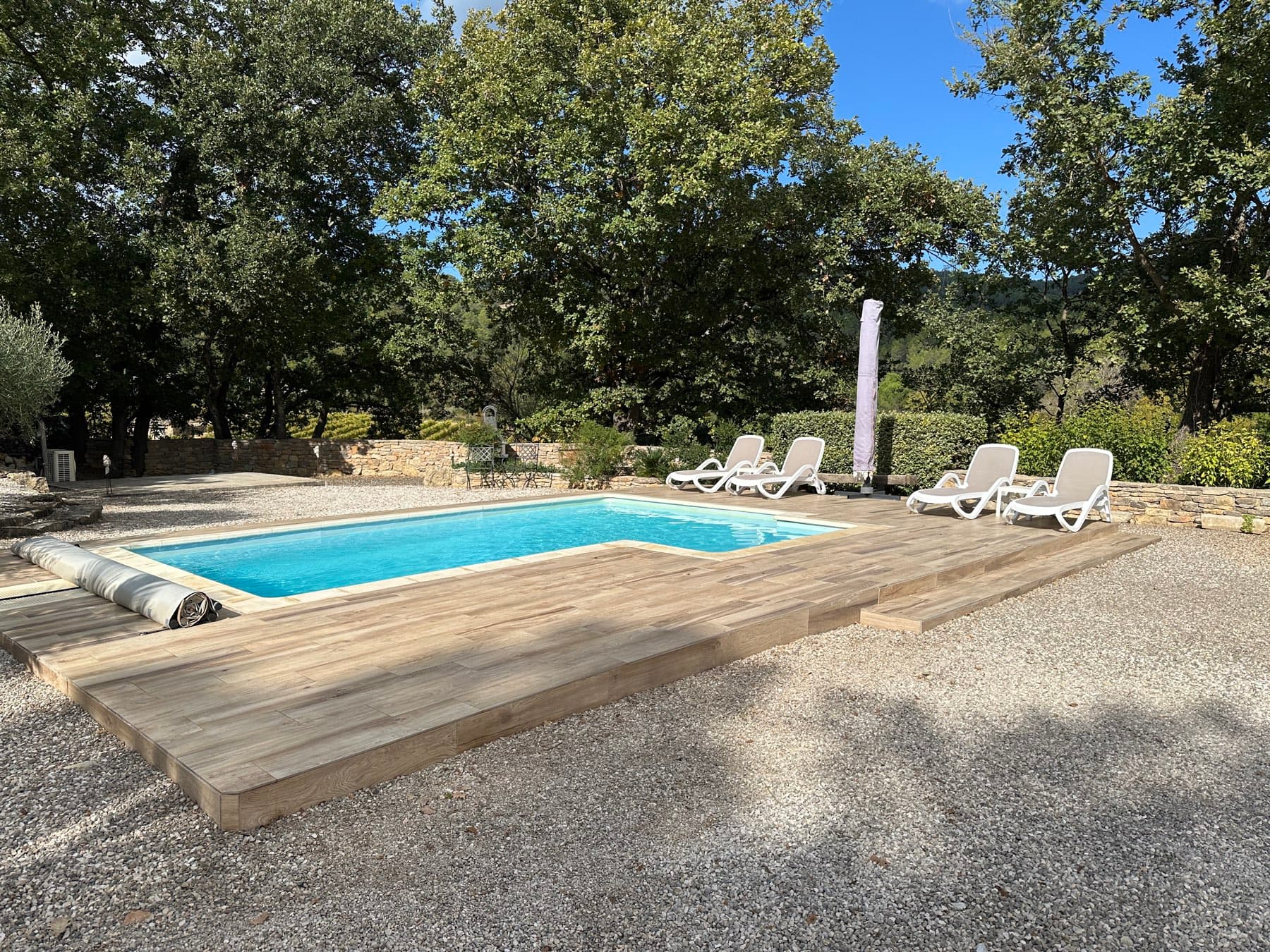 Terrasse en bois avec transats face à la piscine d'une villa varoise